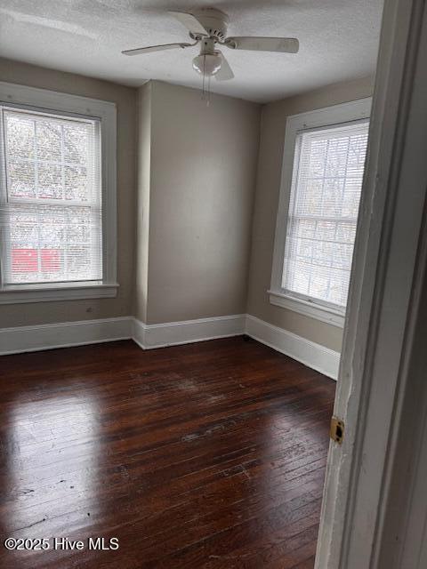 unfurnished room with ceiling fan, a textured ceiling, baseboards, and dark wood-style flooring