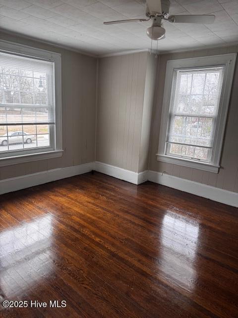 spare room with a ceiling fan, dark wood finished floors, baseboards, and ornamental molding