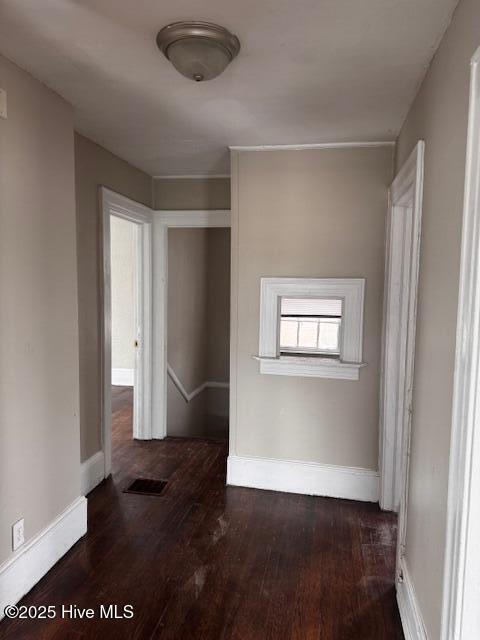 corridor featuring visible vents, baseboards, and wood finished floors