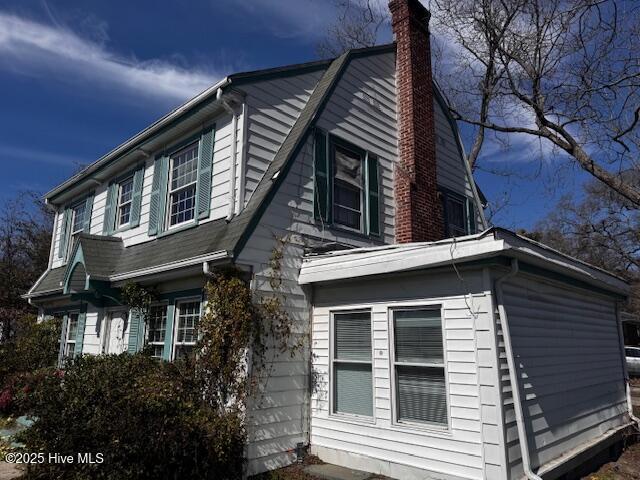 view of side of property featuring a chimney and a gambrel roof