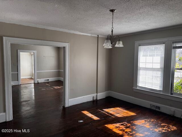 unfurnished dining area with an inviting chandelier, baseboards, visible vents, and dark wood-type flooring