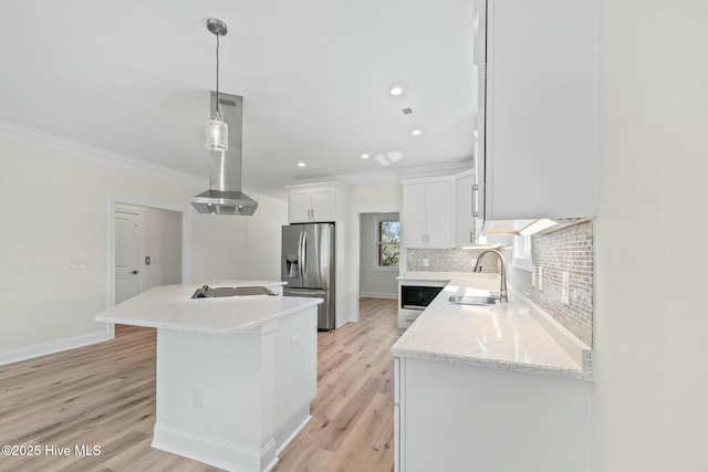 7103 E Yacht Dr, Oak Island, NC 28465 - kitchen featuring a center island with sink, stainless steel fridge with ice dispenser, a sink, decorative backsplash, and wall chimney exhaust hood