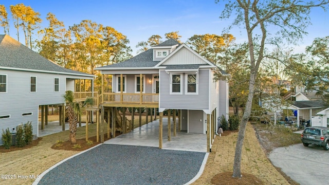 coastal home with a carport, gravel driveway, covered porch, and a shingled roof