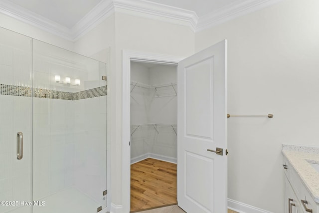 7103 E Yacht Dr, Oak Island, NC 28465 - full bathroom featuring a walk in closet, a shower stall, wood finished floors, and ornamental molding