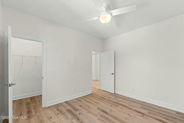 7103 E Yacht Dr, Oak Island, NC 28465 - unfurnished bedroom with light wood finished floors, baseboards, a closet, and a walk in closet