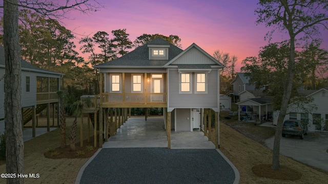 raised beach house featuring a carport, gravel driveway, and a shingled roof