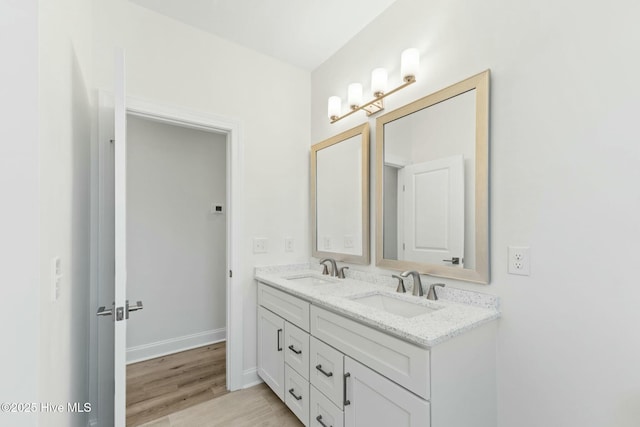 7103 E Yacht Dr, Oak Island, NC 28465 - bathroom featuring a sink, baseboards, wood finished floors, and double vanity