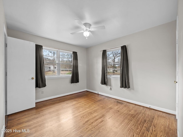 unfurnished room with visible vents, plenty of natural light, and wood finished floors