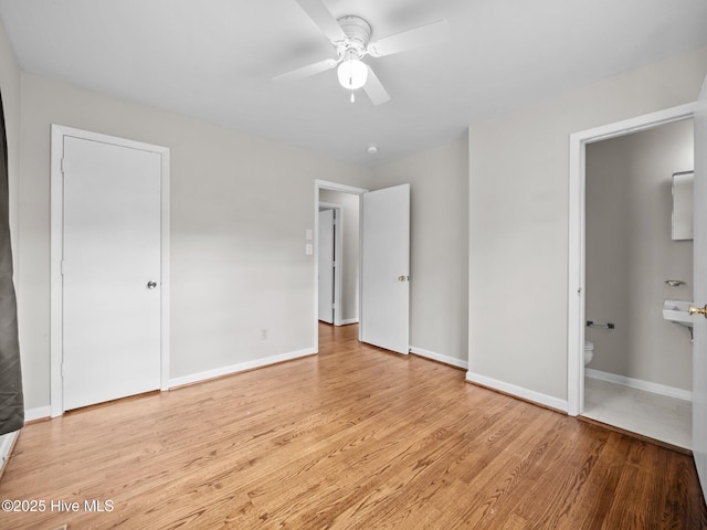 unfurnished bedroom featuring light wood finished floors, a ceiling fan, baseboards, and connected bathroom