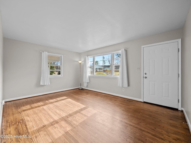 interior space with baseboards, visible vents, and wood finished floors