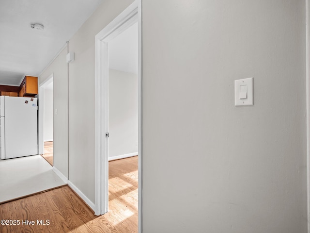 corridor featuring baseboards and wood finished floors