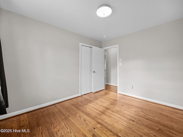 unfurnished bedroom with light wood-style floors, a closet, and baseboards