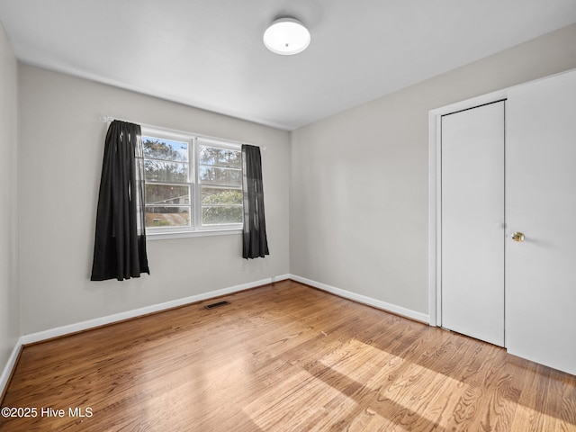 unfurnished bedroom with visible vents, baseboards, and wood finished floors