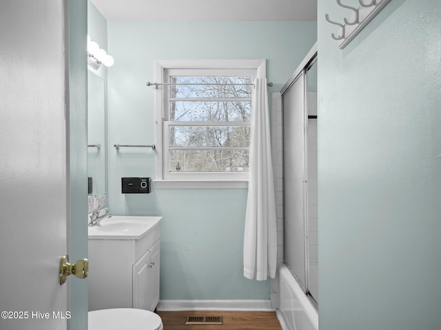 bathroom with shower / bath combination with glass door, wood finished floors, vanity, visible vents, and baseboards