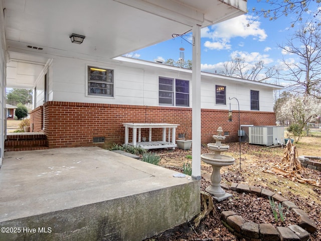 rear view of property with a patio, brick siding, crawl space, and cooling unit