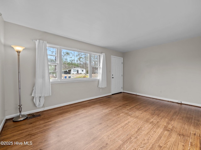 unfurnished living room with visible vents, baseboards, and wood finished floors