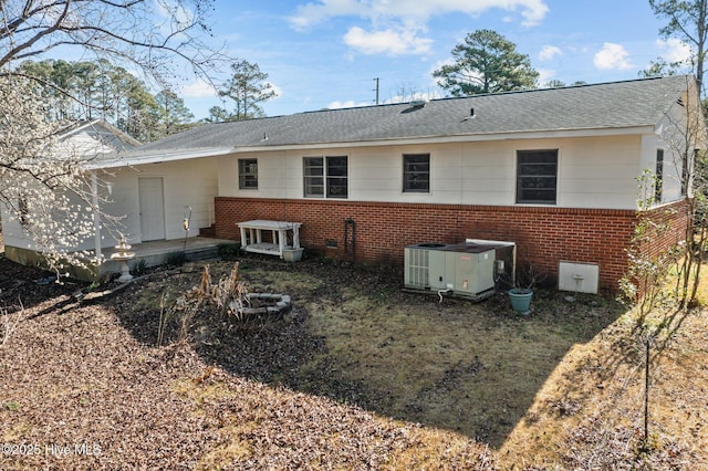 rear view of house featuring a shingled roof, crawl space, brick siding, and central AC unit