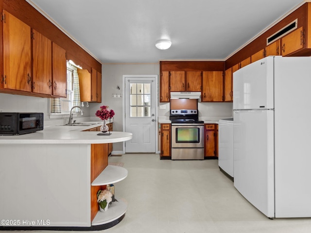 kitchen with under cabinet range hood, a sink, stainless steel electric range, freestanding refrigerator, and brown cabinetry