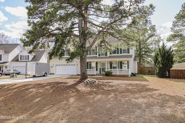 colonial-style house with covered porch, concrete driveway, and fence