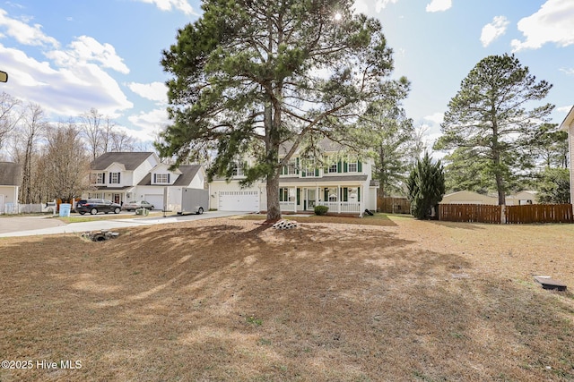 view of front of property with a garage, covered porch, concrete driveway, and fence