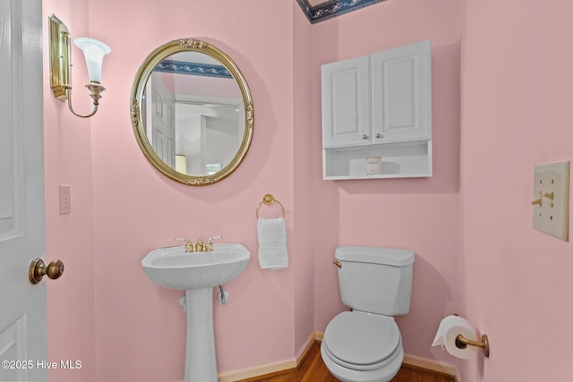 bathroom with baseboards, toilet, and wood finished floors