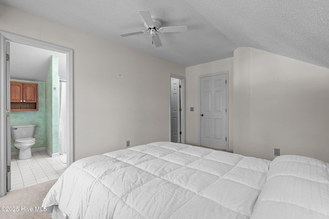 tiled bedroom with connected bathroom, a ceiling fan, carpet floors, and a textured ceiling