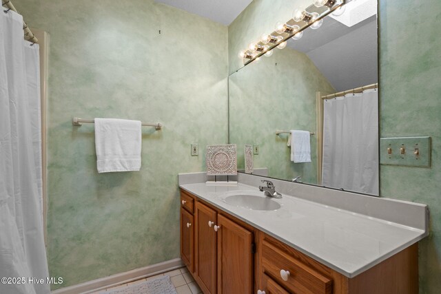 bathroom with vanity, tile patterned floors, and lofted ceiling with skylight