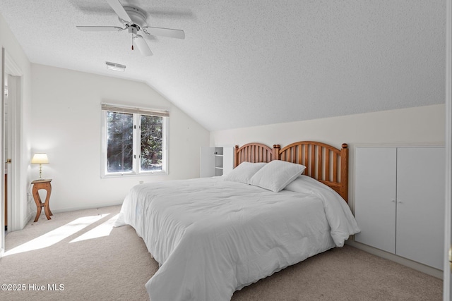 bedroom featuring visible vents, a ceiling fan, a textured ceiling, carpet flooring, and vaulted ceiling