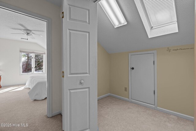 bonus room featuring baseboards, vaulted ceiling with skylight, a textured ceiling, and carpet