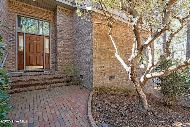 view of exterior entry featuring crawl space and brick siding