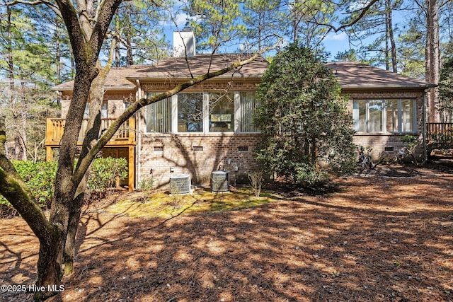 rear view of property featuring crawl space, central AC, a chimney, and brick siding