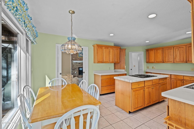 kitchen featuring light tile patterned floors, a fireplace, hanging light fixtures, light countertops, and a center island