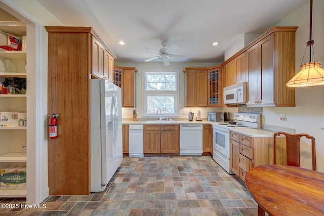 kitchen featuring light countertops, white appliances, a sink, and glass insert cabinets