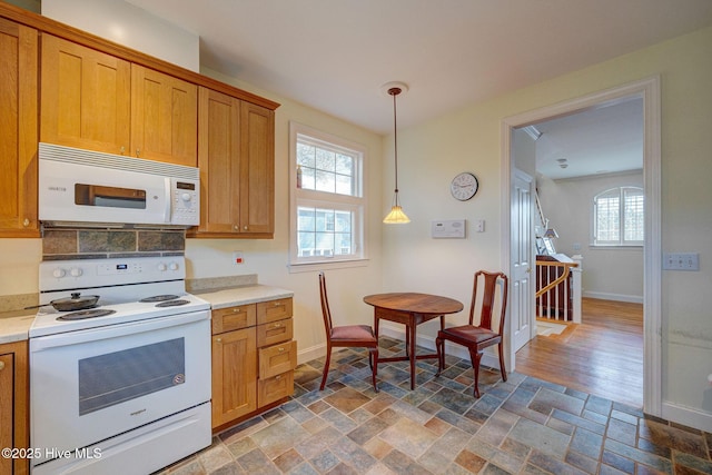 kitchen with stone finish flooring, white appliances, light countertops, and baseboards