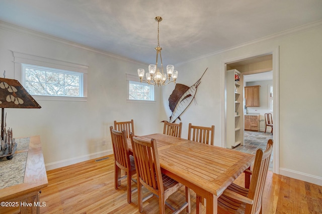 dining room with baseboards, light wood-type flooring, and crown molding