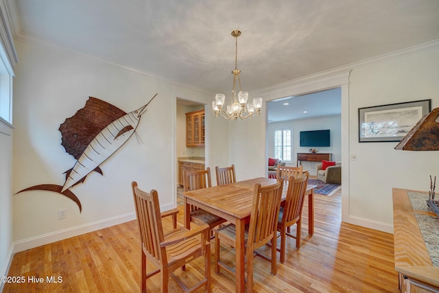 dining area featuring light wood-style flooring, baseboards, and ornamental molding