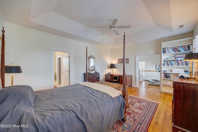 bedroom featuring light wood-style floors, a tray ceiling, and visible vents