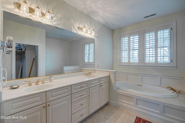 full bath featuring a bath, double vanity, visible vents, and a sink