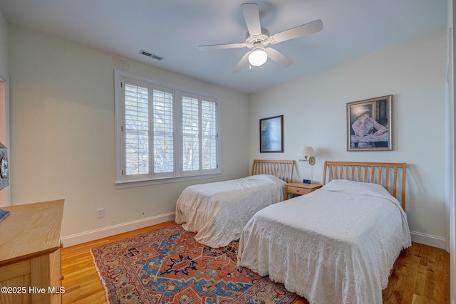 bedroom with baseboards, visible vents, ceiling fan, and wood finished floors