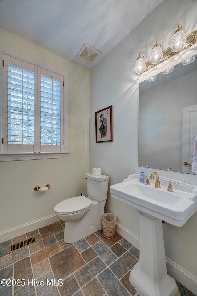 half bathroom with toilet, visible vents, and baseboards