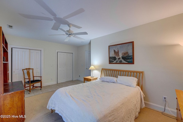 bedroom featuring multiple closets, visible vents, light carpet, and baseboards