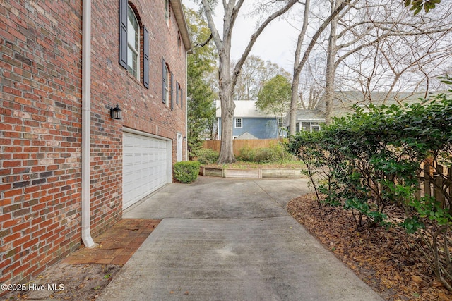 exterior space featuring concrete driveway, fence, and an attached garage