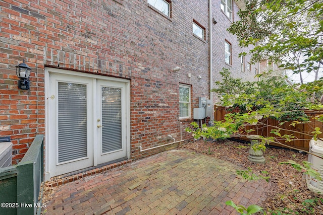 doorway to property with brick siding, a patio area, and fence