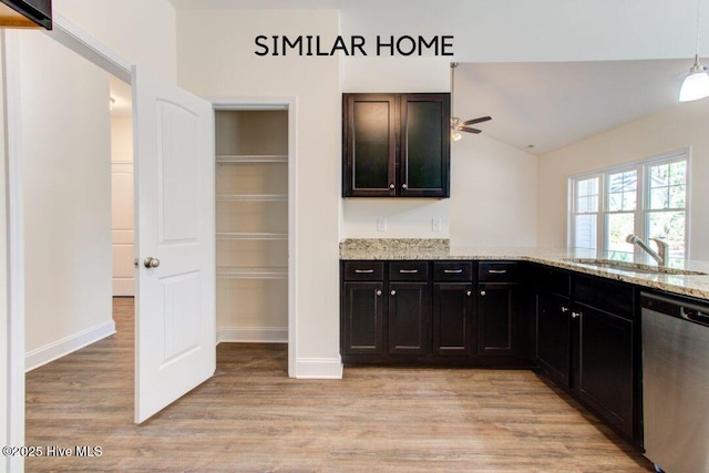 kitchen featuring light wood finished floors, ceiling fan, light stone counters, stainless steel dishwasher, and a sink