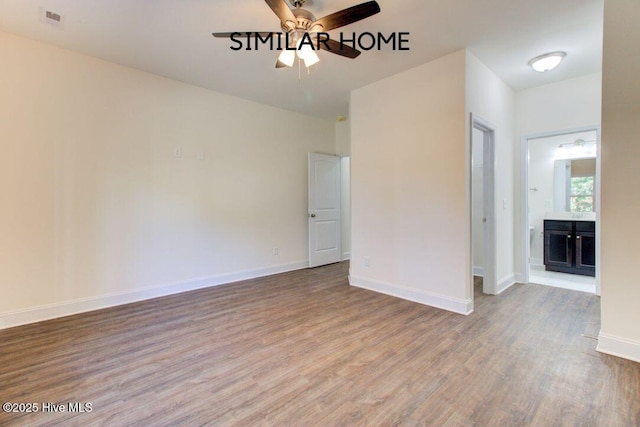 empty room featuring ceiling fan, a fireplace, baseboards, and wood finished floors