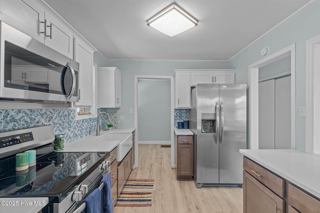 kitchen with white cabinets, appliances with stainless steel finishes, light countertops, and a sink