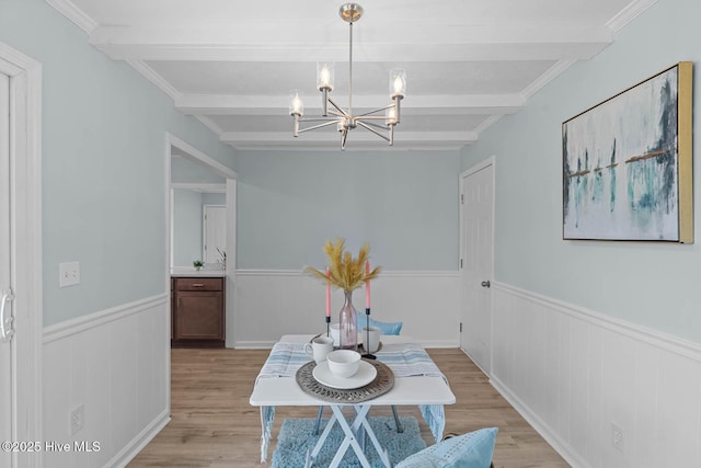 dining area featuring a wainscoted wall, beamed ceiling, light wood-type flooring, and a chandelier