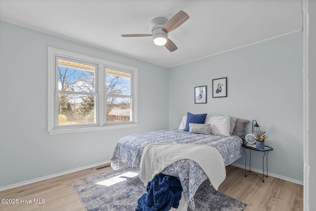 bedroom with ceiling fan, baseboards, and wood finished floors