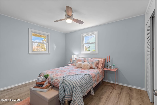 bedroom with baseboards, multiple windows, a closet, and wood finished floors