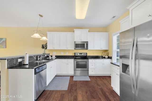 kitchen with white cabinetry, a peninsula, dark wood-type flooring, and stainless steel appliances